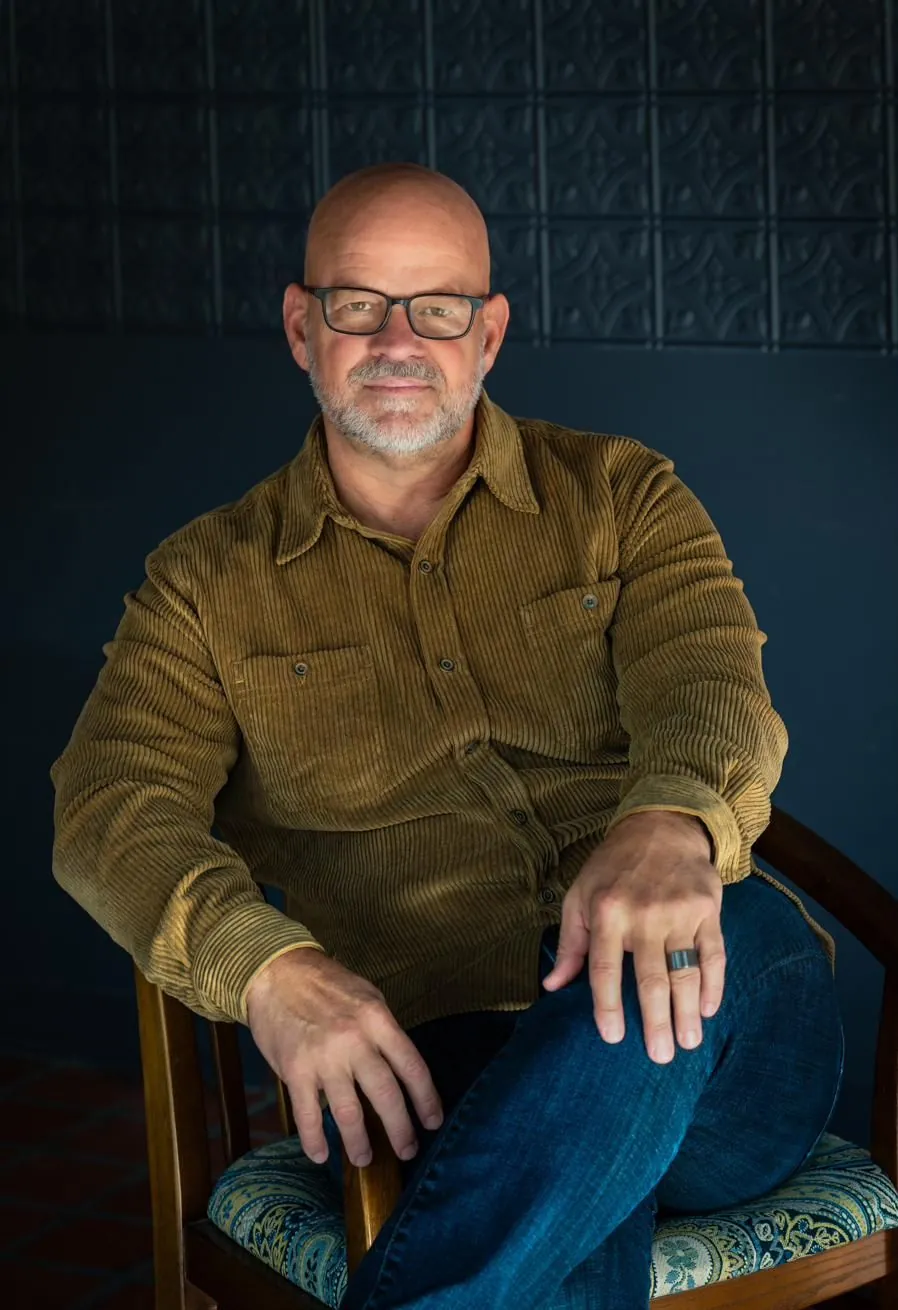 Troy Murphy in glasses and an olive shirt, seated
