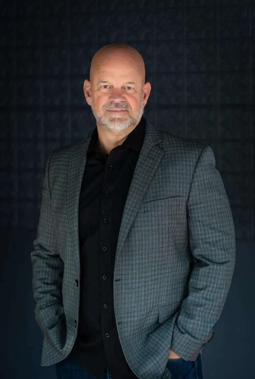 Troy Murphy in a grey plaid jacket against a dark pressed-tin wall